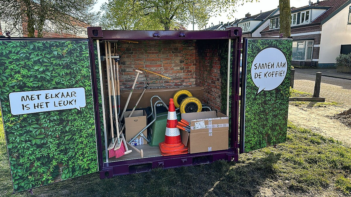 de vrijwilligerscontainer met een kruiwagen en bezems